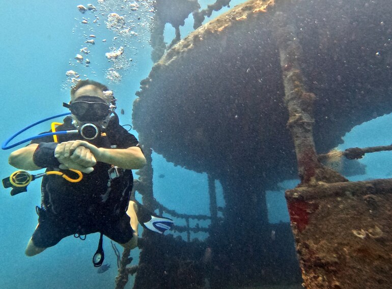 Advanced diver checking time and depth beside a wreck in Bayahibe