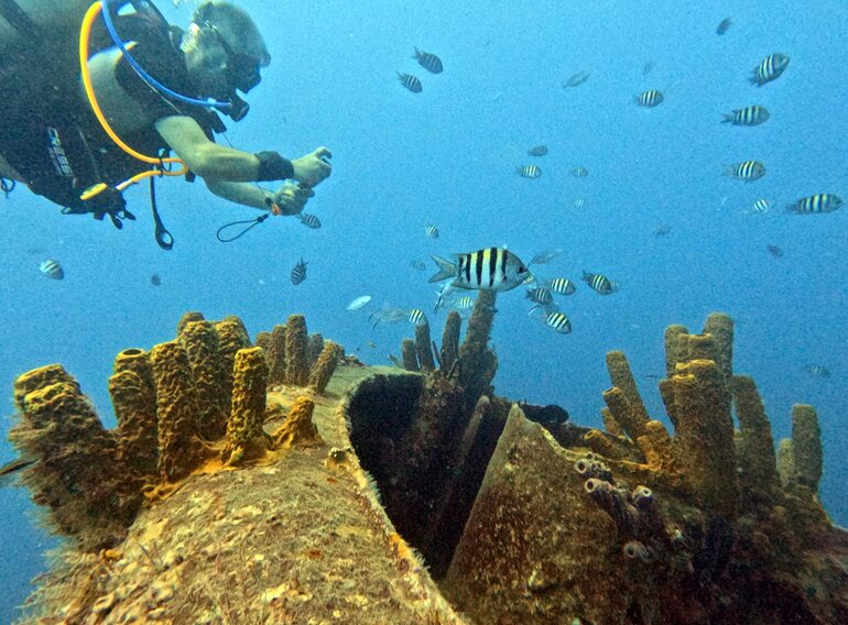 Advanced Open Water diver practising controlled buoyancy above a Caribbean reef with tropical fish