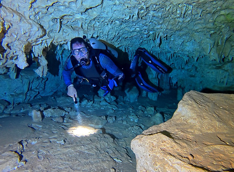 Scuba diver exploring limestone formations inside Padre Nuestro cavern near Bayahibe