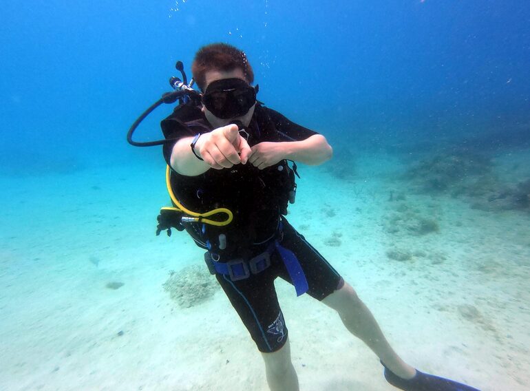 Divemaster candidate using clear underwater communication during leadership training near Bayahibe