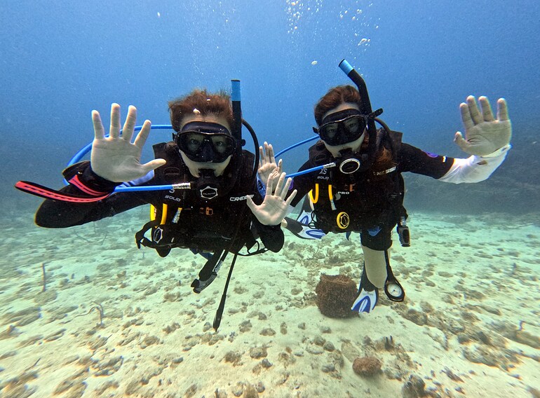 Two beginner scuba divers enjoying relaxed small-group diving in the Caribbean Sea near Bayahibe