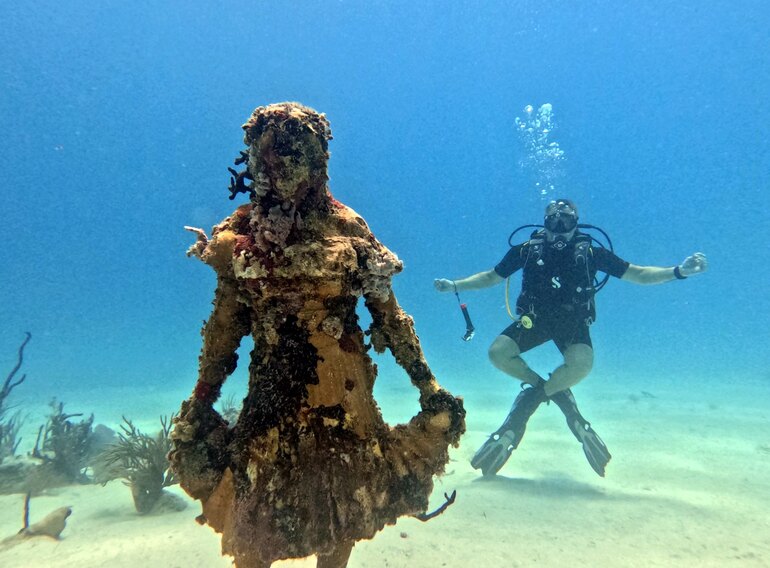 Scuba diver beside an underwater statue near Bayahibe